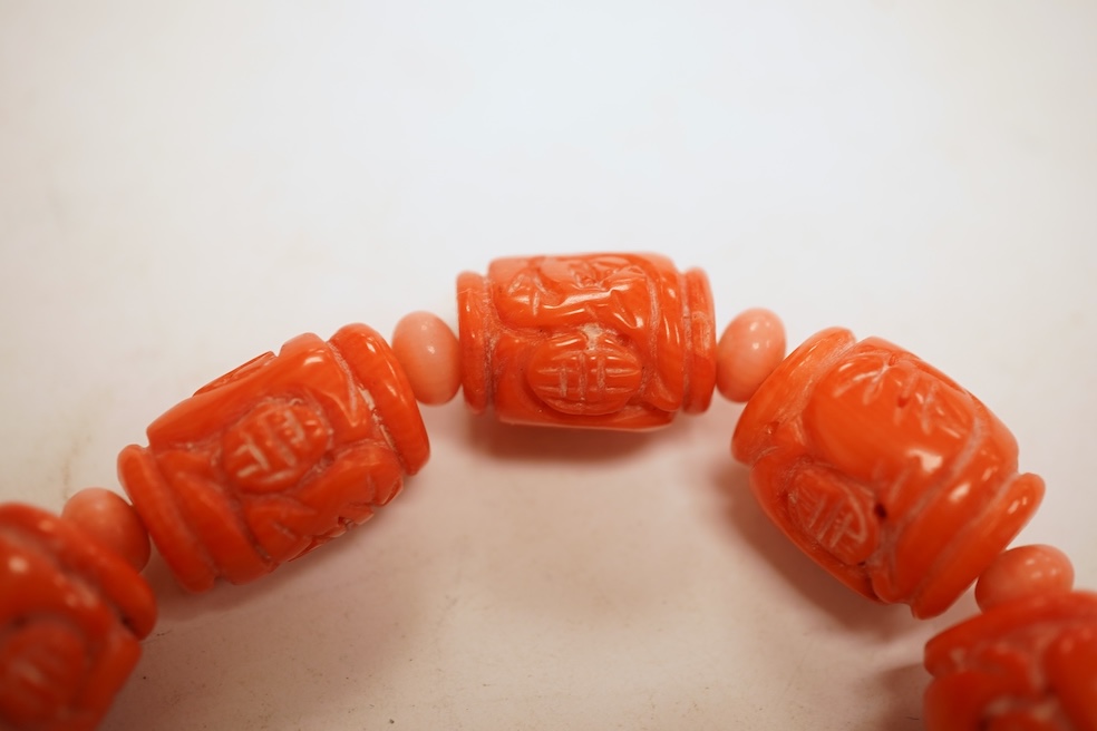 Two coral bead necklaces, one composed of large cylindrical coral beads, approximately 2.5-3.5cm each, total length 49cm; and a bracelet composed of carved coral beads spaced by smaller pink coral beads, on an elasticate